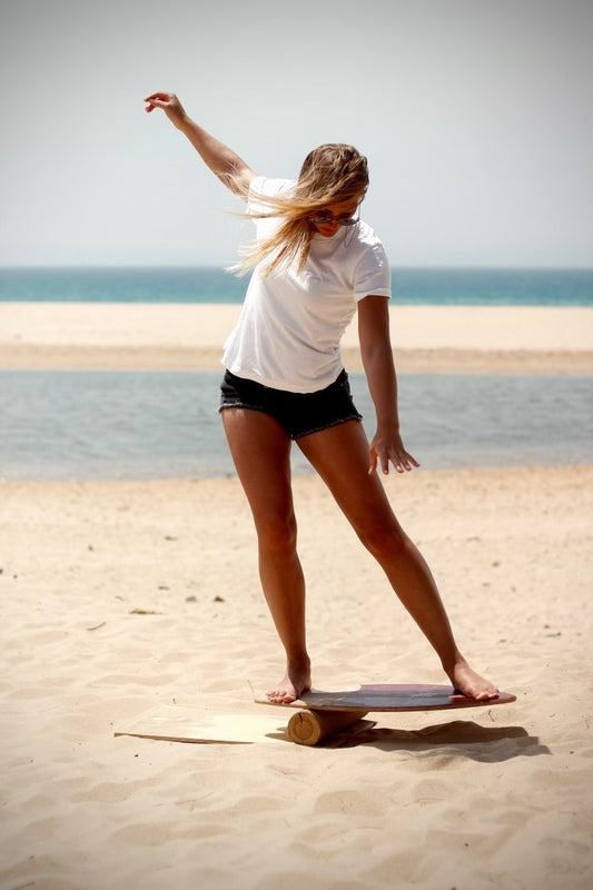 Junge Frau auf dem Balance Board am Strand